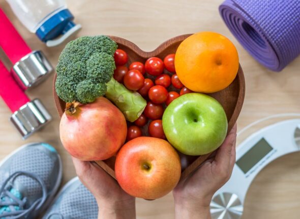 Healthy lifestyle concept, clean food good health dietary in heart dish with sporty gym aerobic body exercise workout training class equipment, weight scale and sports shoes in fitness center